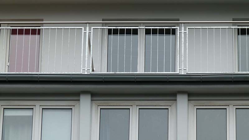 Ein Balkon mit einem Metallgeländer an der Seite eines Gebäudes mit vielen Fenstern.