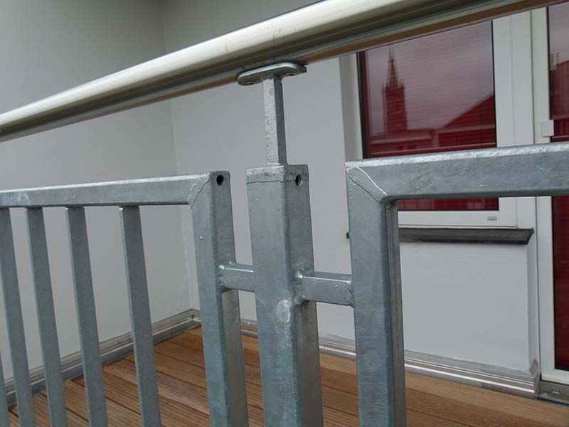 Eine Nahaufnahme eines Metallgeländers auf einem Balkon mit einem Fenster im Hintergrund.