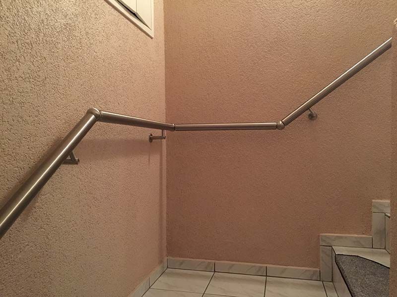 Eine Treppe mit einem Edelstahlhandlauf an der Wand