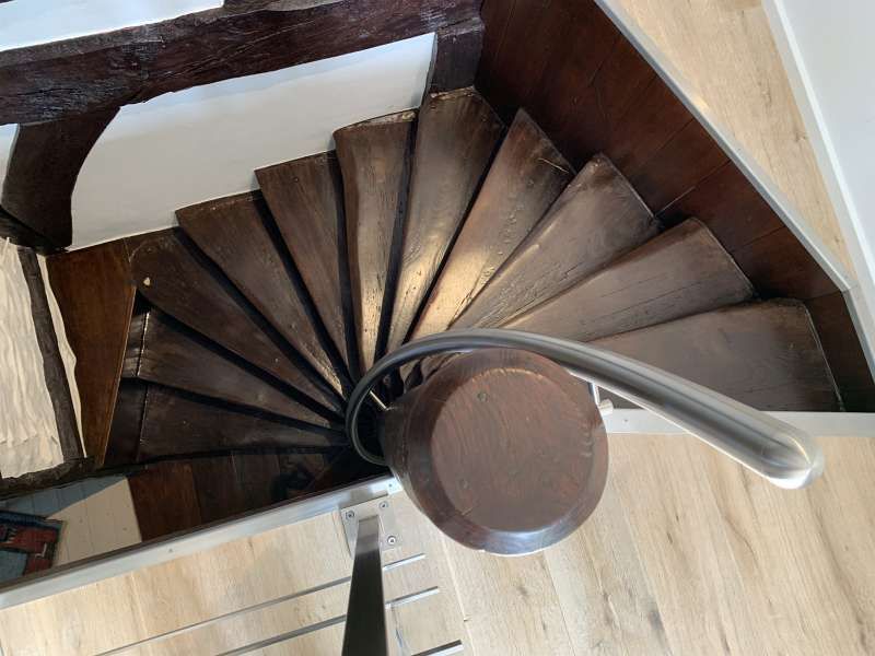 Eine hölzerne Wendeltreppe mit einem Metallgeländer in einem Haus.