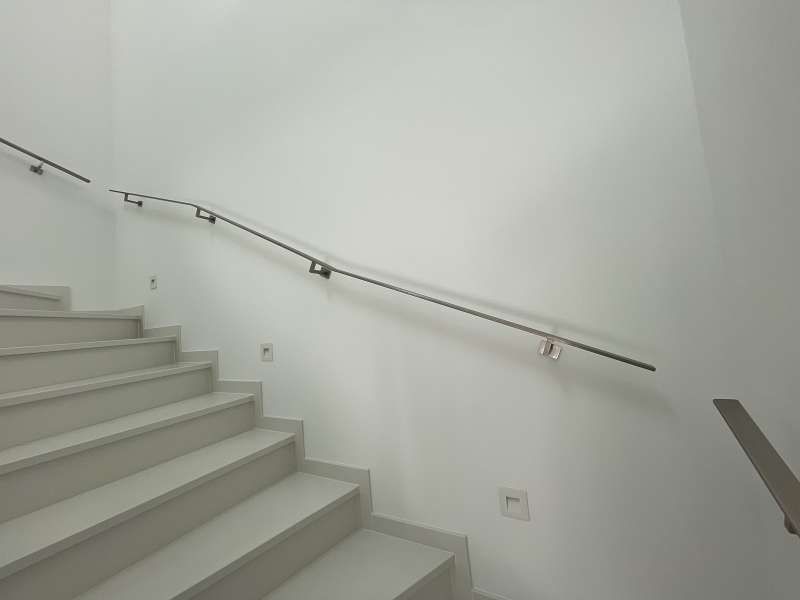 Eine Treppe mit einem Metallgeländer vor einer weißen Wand.