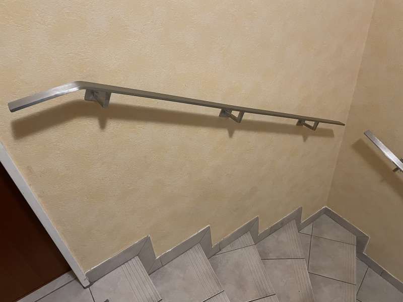 Eine Treppe mit einem Edelstahlhandlauf an der Wand.