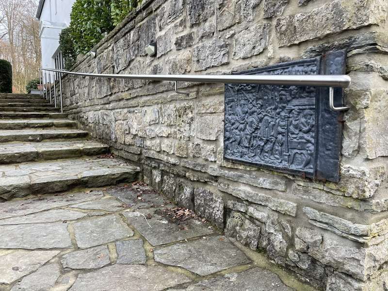 Eine Steinmauer mit hinaufführenden Stufen und einem Metallgeländer.