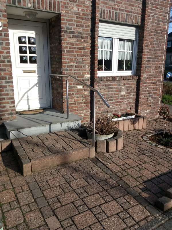 Ein Backsteingebäude mit einer weißen Tür und einem Metallgeländer