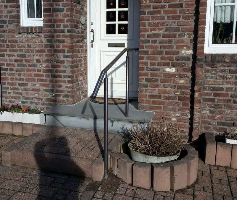 Ein Backsteingebäude mit einer weißen Tür und einem Metallgeländer