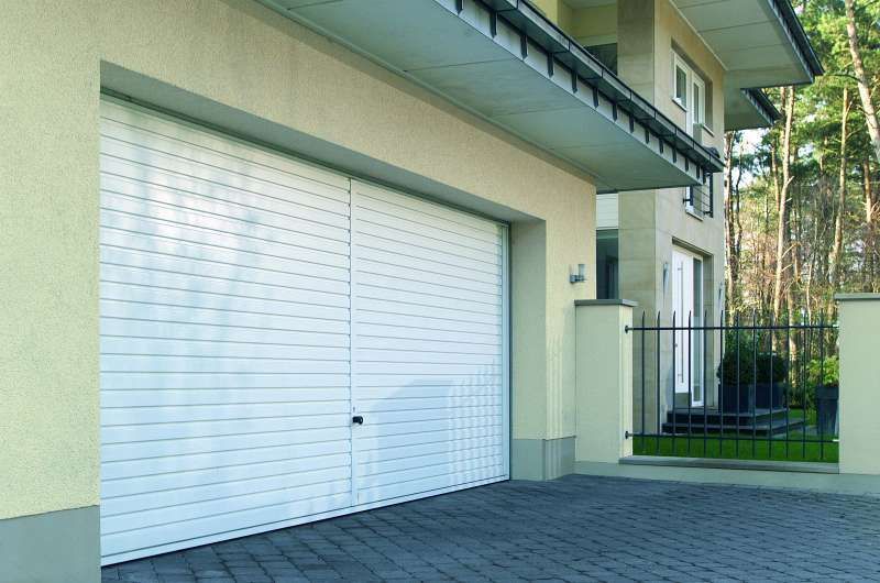 Vor einem Haus steht ein weißes Garagentor.