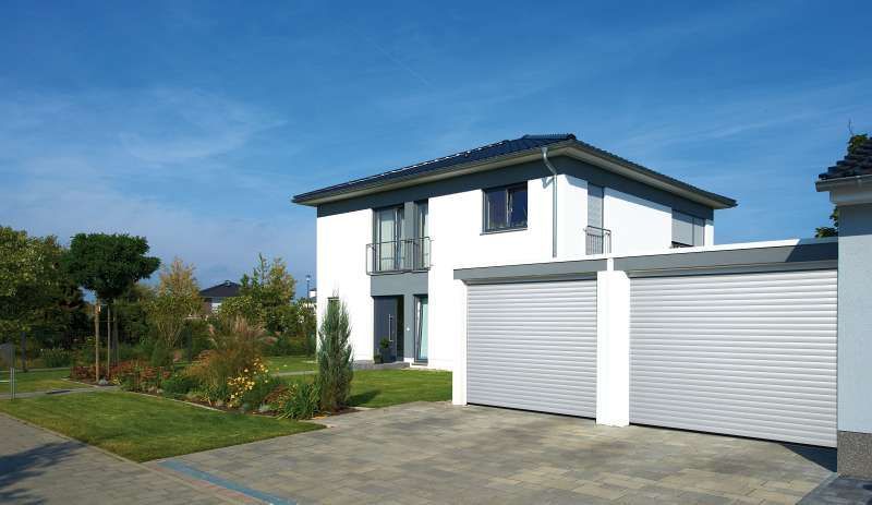 Ein weißes Haus mit einer Garage und einer Auffahrt davor.