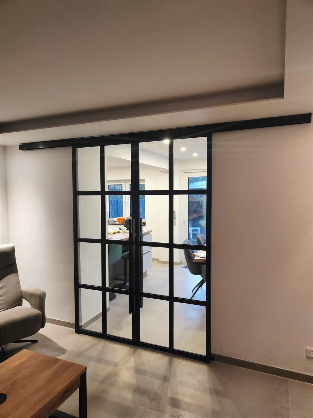 Ein Wohnzimmer mit einer Glasschiebetür zwischen Küche und Esszimmer.