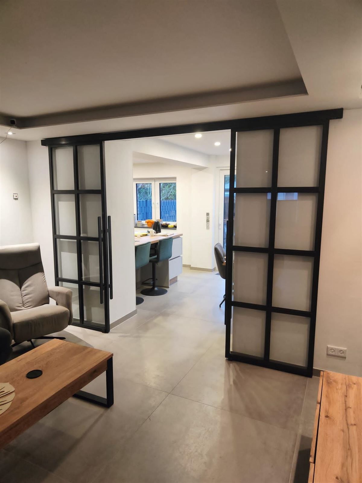 Ein Wohnzimmer mit Couch, Sessel, Couchtisch und Glasschiebetüren.