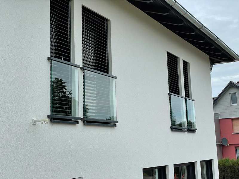 Ein weißes Haus mit vielen Fenstern und Fensterläden