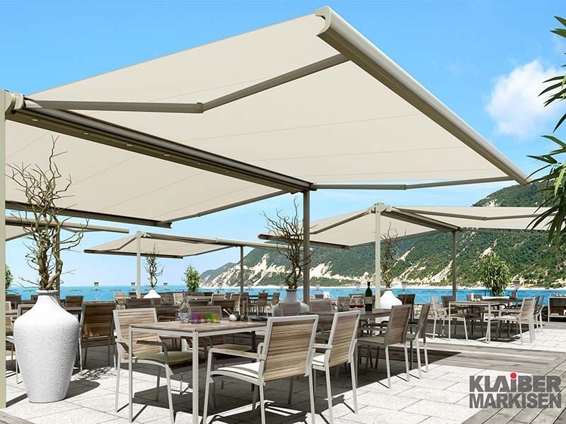 Ein Restaurant mit Tischen und Stühlen unter einer Markise mit der Aufschrift „Klaiber Markisen“