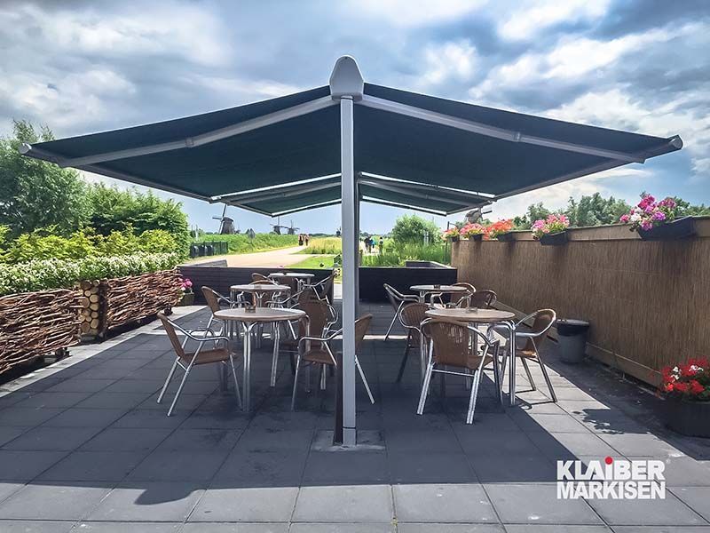 Eine Terrasse mit Tischen und Stühlen unter einem großen Sonnenschirm