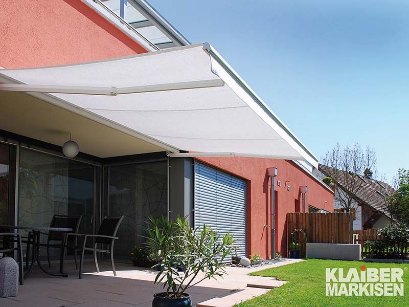 Ein rotes Haus mit einer weißen Markise auf der Terrasse