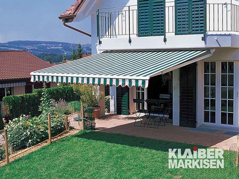 Ein Haus mit einer grün-weißen Markise auf der Terrasse