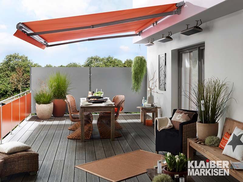 Ein Balkon mit einer roten Markise und einem Tisch und Stühlen