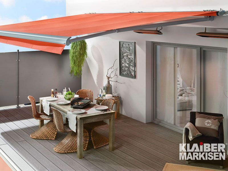 Eine Terrasse mit Tisch und Stühlen unter einer orangefarbenen Markise.