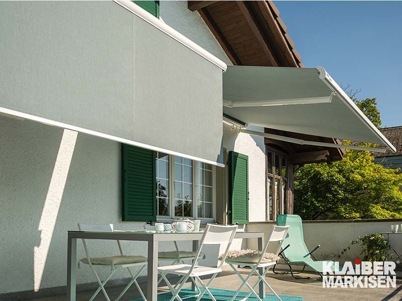 Ein weißes Haus mit einem Tisch und Stühlen unter einer Markise