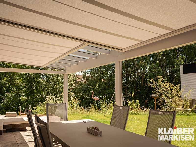 Eine Terrasse mit einem Tisch und Stühlen unter einem Baldachin mit einem Flamingo im Hintergrund.