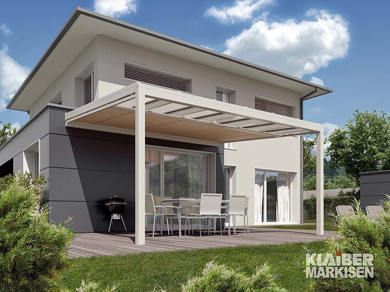 Ein Haus mit einer Pergola und einem Tisch und Stühlen auf der Terrasse.