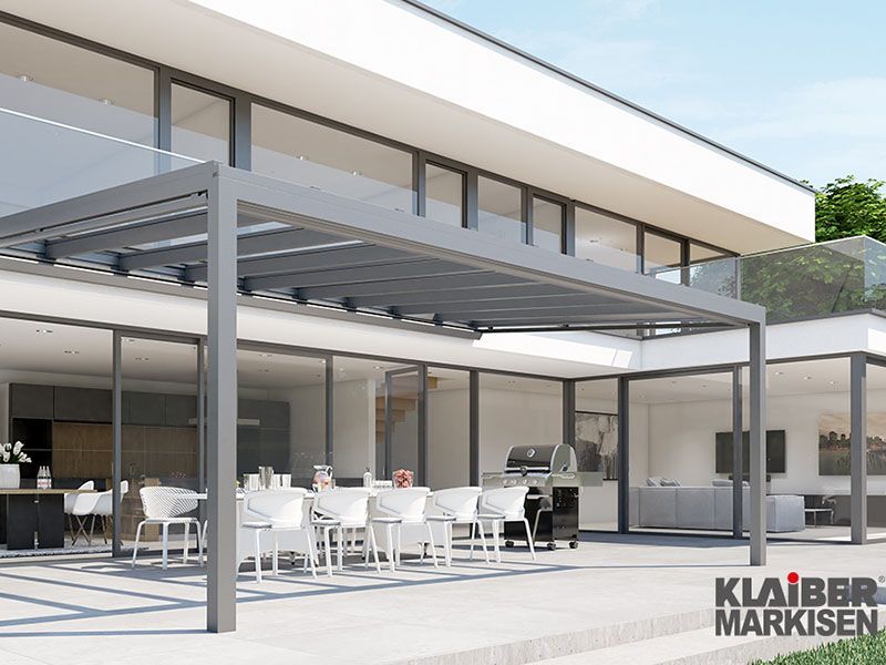 Ein großes Haus mit Pergola und Tischen und Stühlen