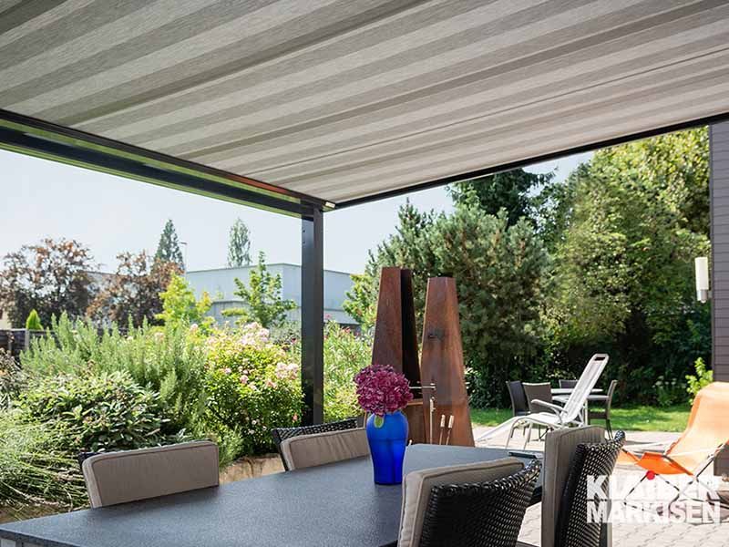 Eine Terrasse mit Tisch und Stühlen unter einem Baldachin.