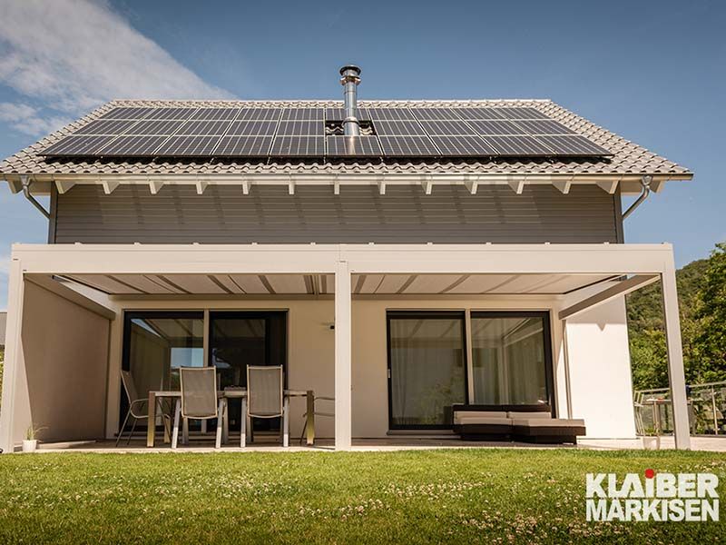 Ein Haus mit Pergola und Sonnenkollektoren auf dem Dach