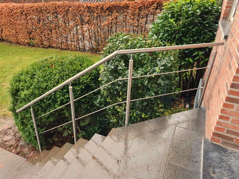 Eine Treppe mit einem Edelstahlgeländer führt zu einem Backsteingebäude.