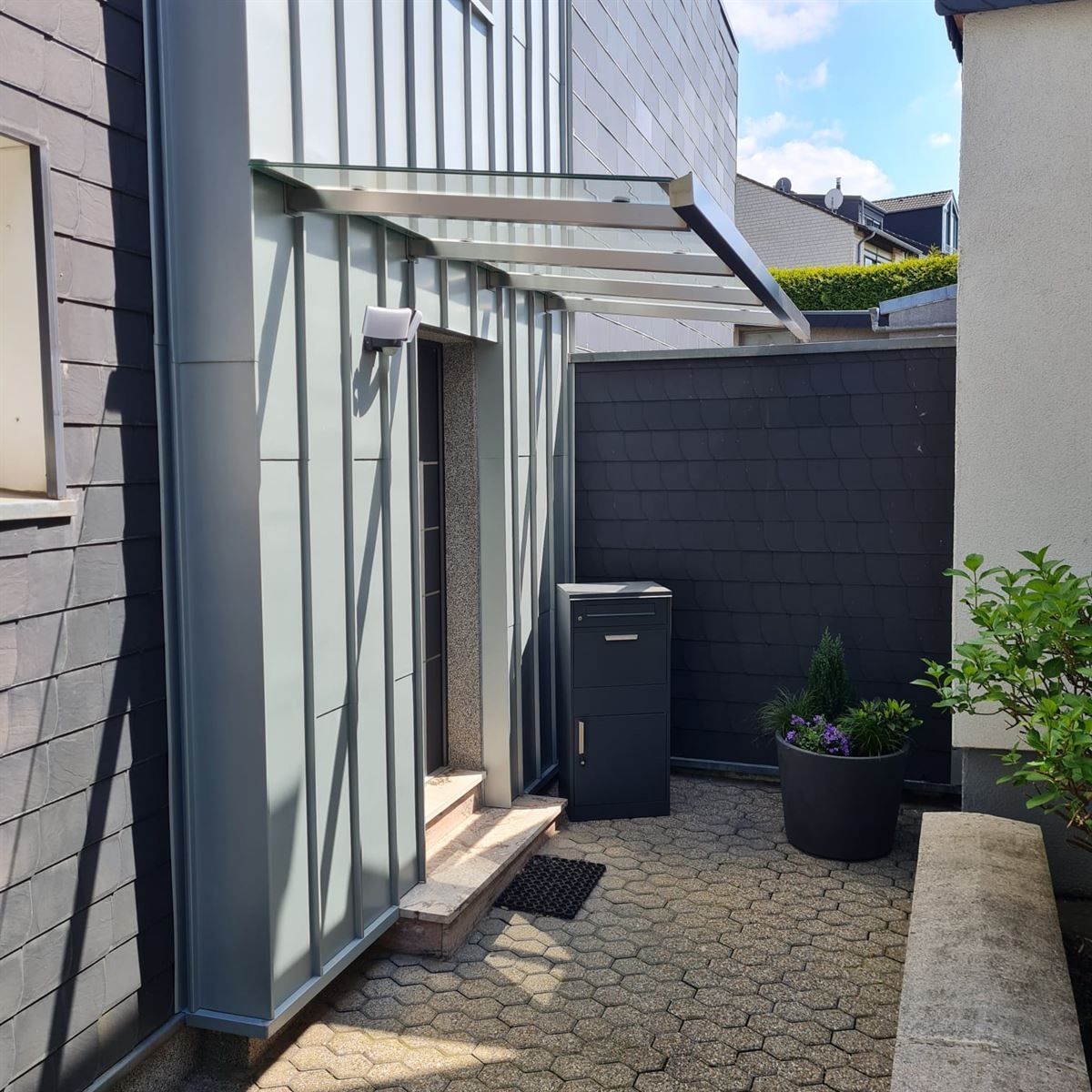 Eine Tür mit einem Vordach darüber und einem Briefkasten