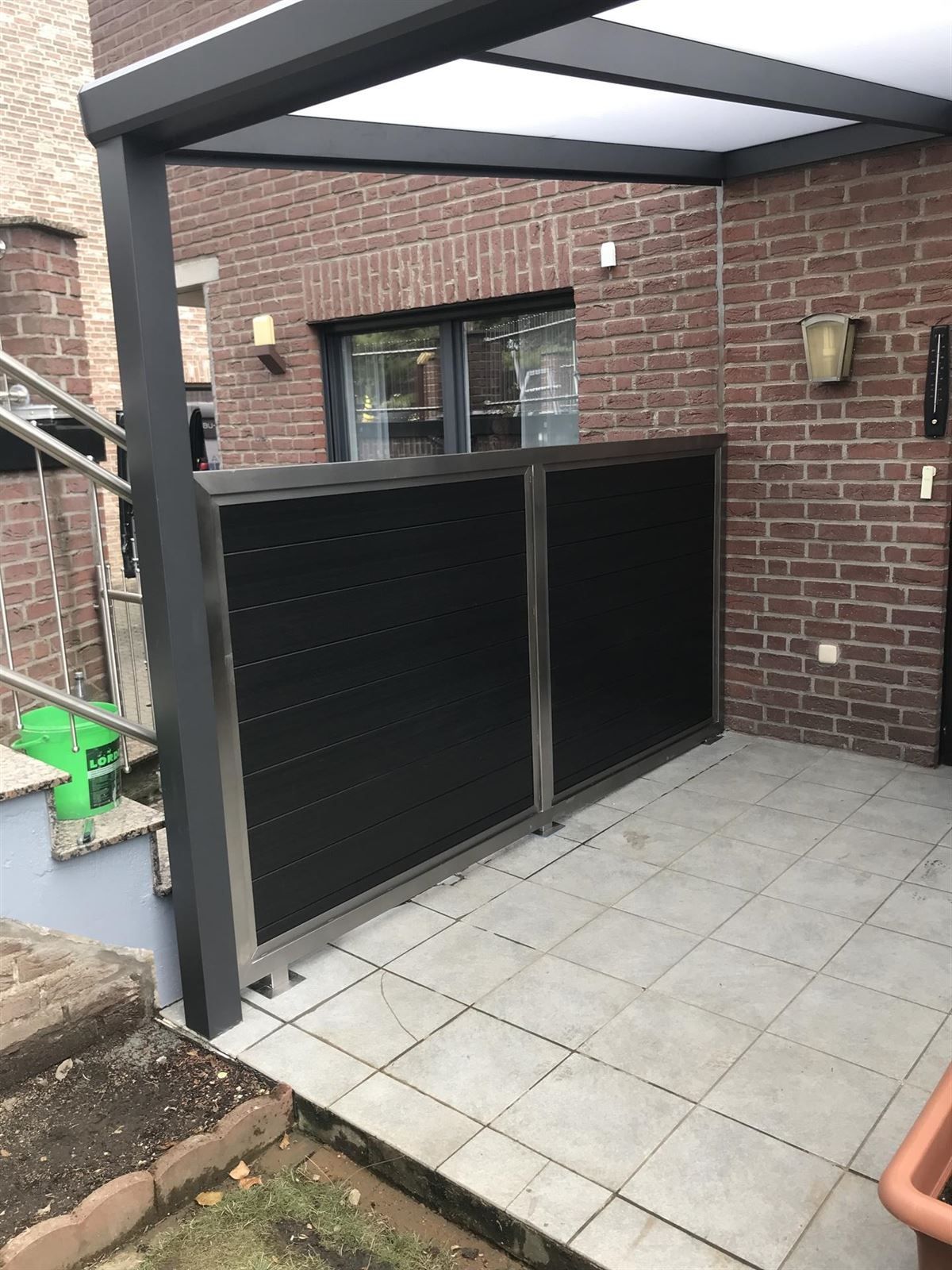 Eine Terrasse mit Pergola und Backsteinmauer