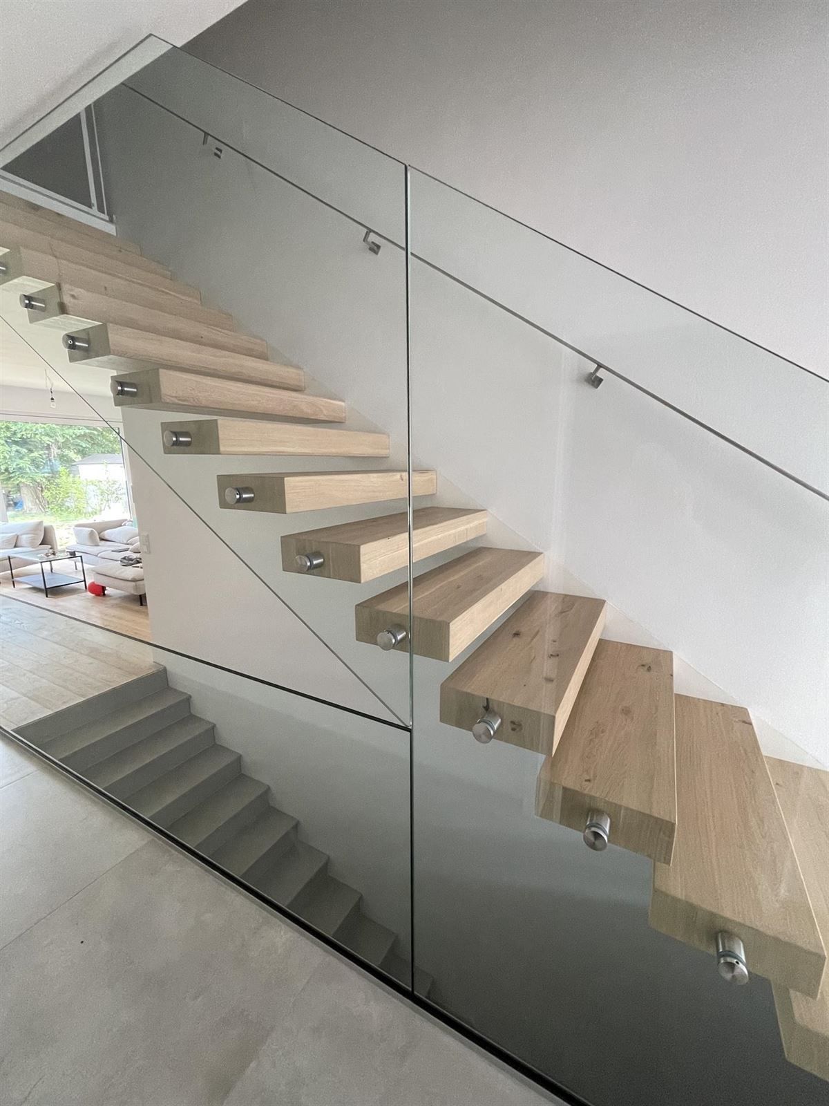 Eine Holztreppe mit einem Glasgeländer in einem Haus.