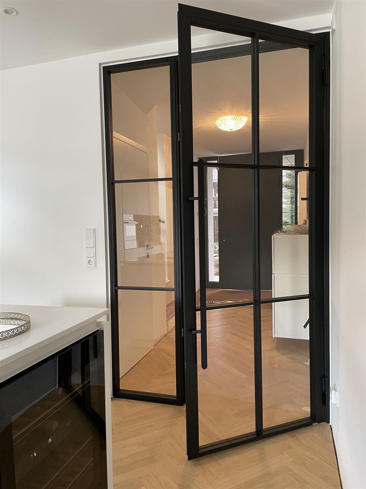 Eine Küche mit Glastür, die zum Wohnzimmer führt.