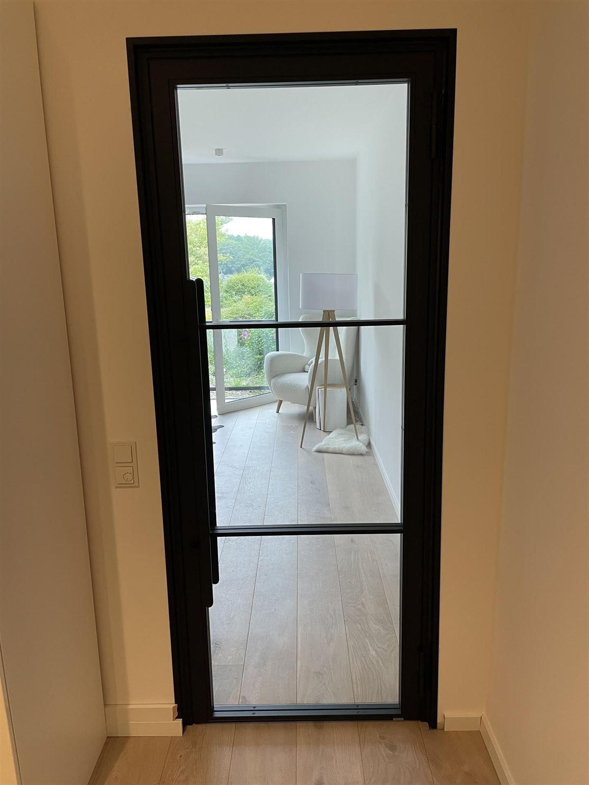 Eine schwarze Tür führt zu einem Wohnzimmer.