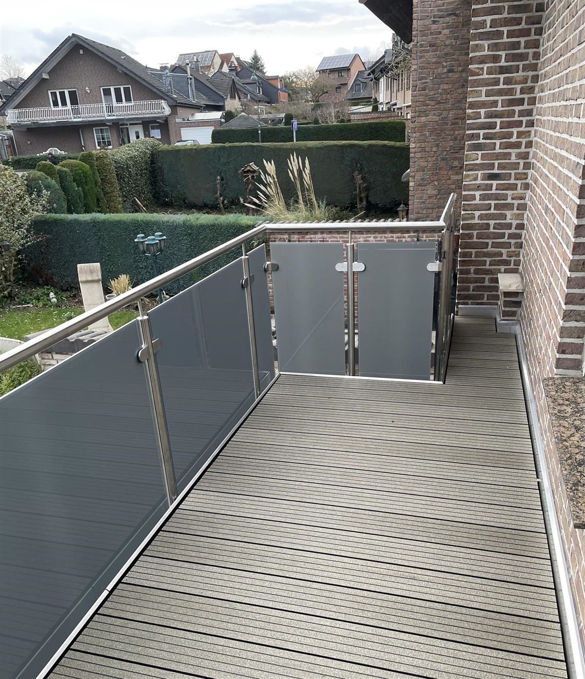 Ein Balkon mit Edelstahlgeländer und im Hintergrund ein Backsteingebäude.