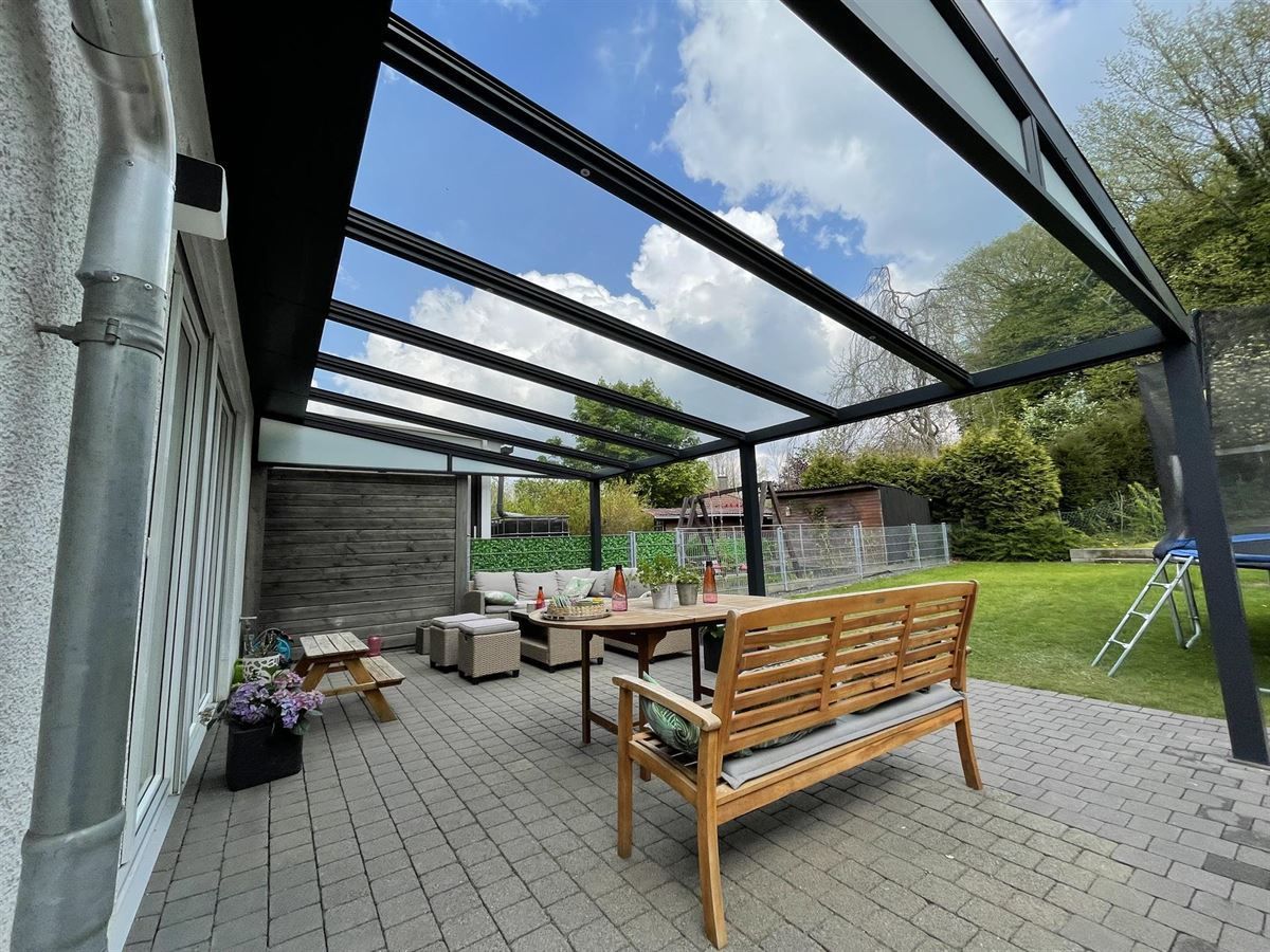 Eine Terrasse mit einer Bank und einem Tisch unter einem Baldachin