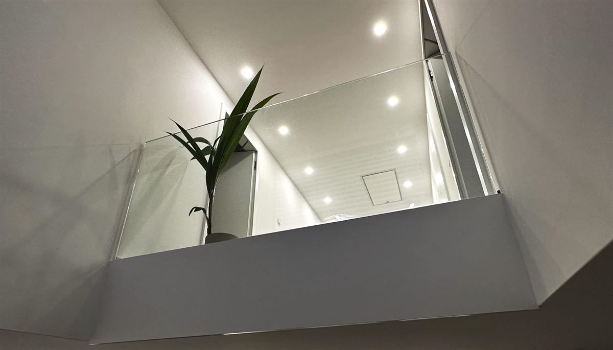 Auf einem Balkon neben einer Treppe steht eine Topfpflanze.