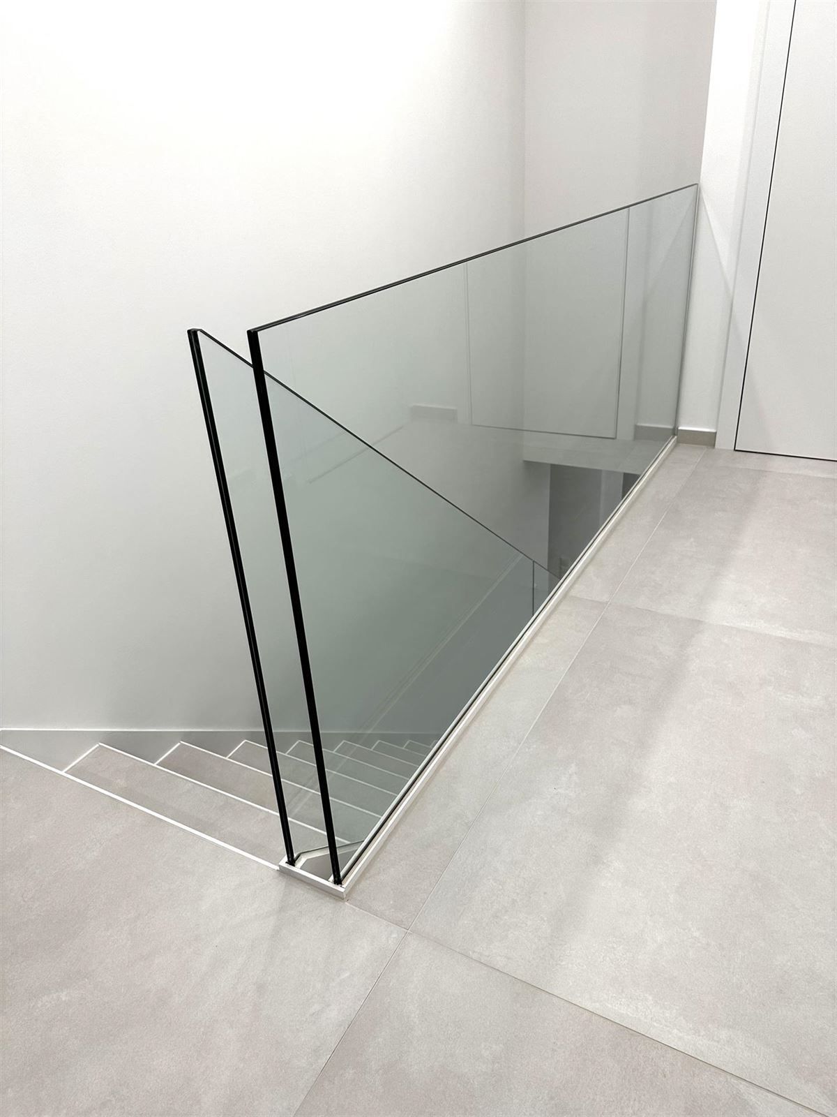 Eine Treppe mit Glasgeländer und gefliestem Boden.