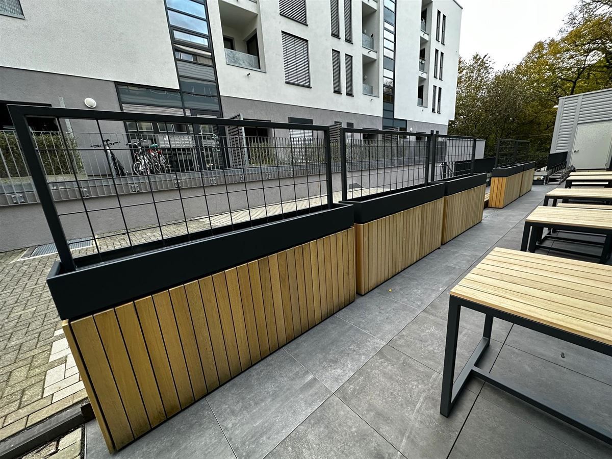 Eine Terrasse mit Holzbänken und Tischen vor einem Gebäude.