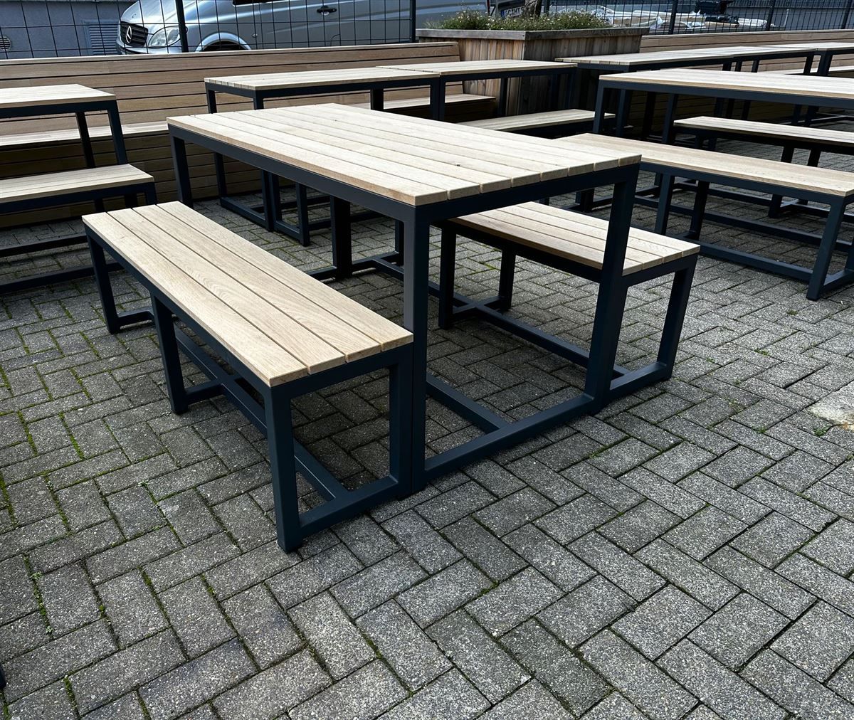 Eine Reihe von hölzernen Picknicktischen und Bänken auf einer gemauerten Terrasse