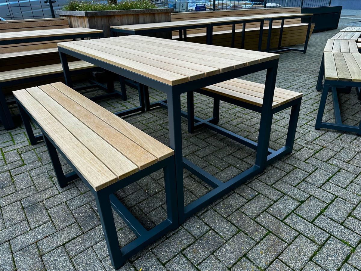 Ein Holztisch und Bänke stehen auf einem Ziegelsteinpflaster.