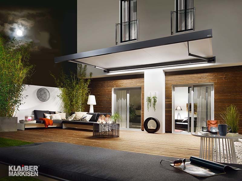 Eine Terrasse mit einer Couch und einem Tisch vor einem Haus.