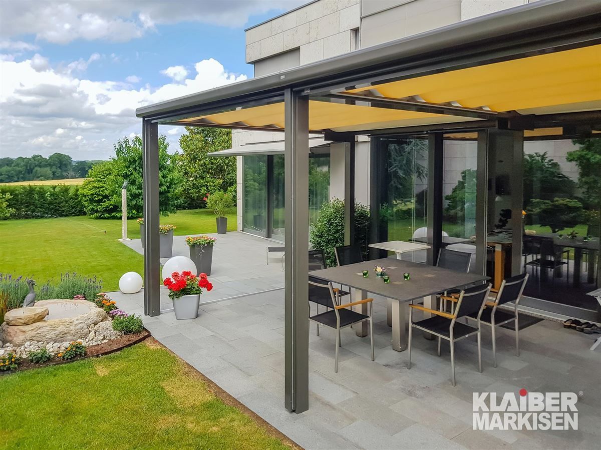 Eine Terrasse mit Tisch und Stühlen unter einem Baldachin.