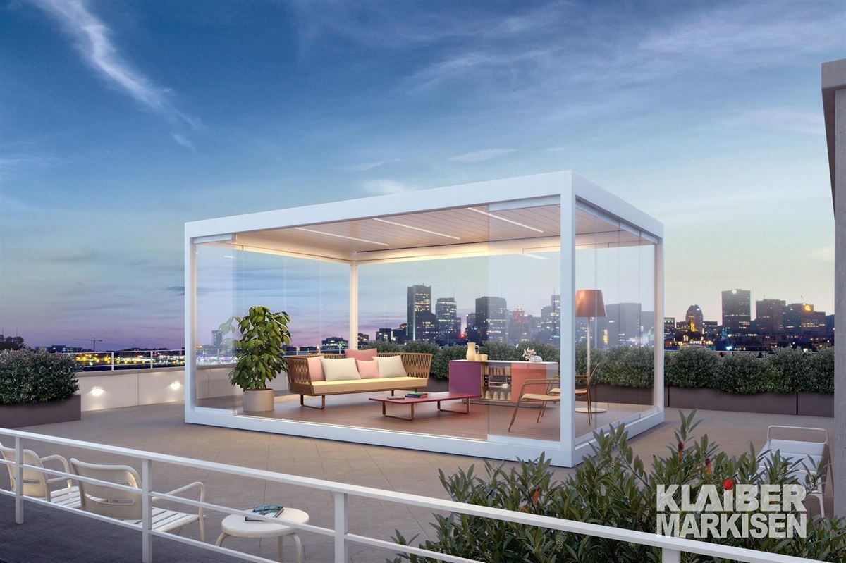 Eine weiße Pergola mit einem Sofa und Stühlen auf einem Dach mit einer Stadt im Hintergrund.