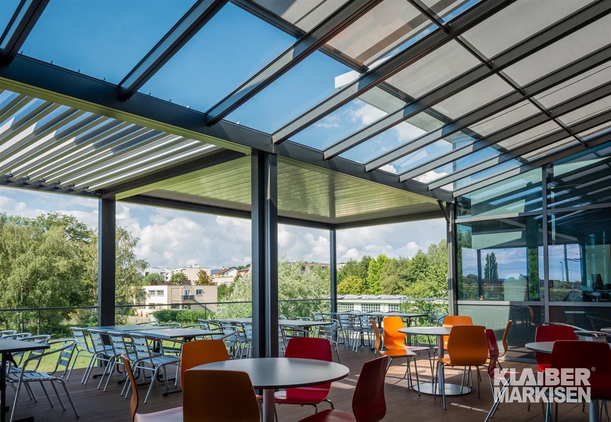 Ein Restaurant mit Tischen und Stühlen unter einem Glasdach