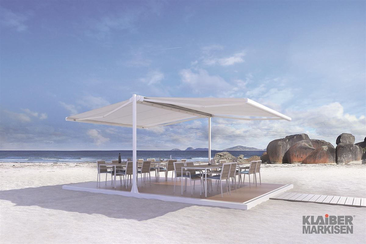 Ein Strand mit Tischen und Stühlen unter einem Sonnenschirm.