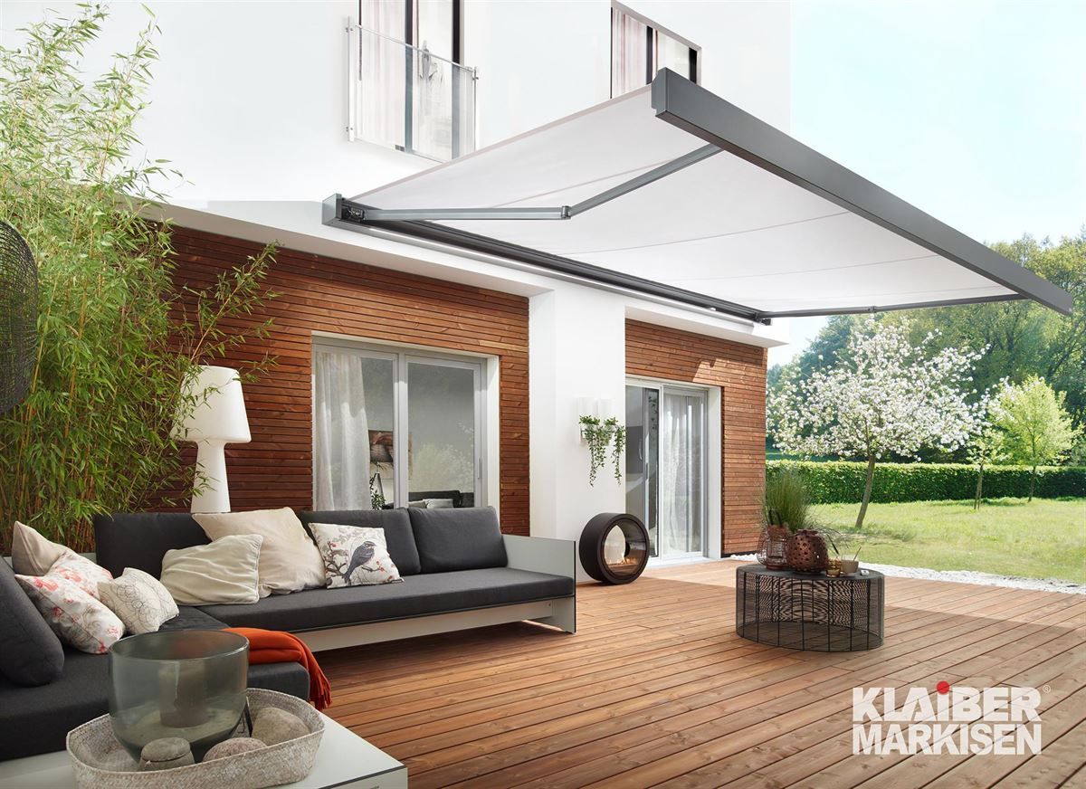 Eine Terrasse mit Couch und Tisch unter einer Markise.