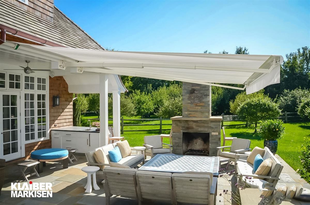 Eine Terrasse mit Kamin und Couch unter einer Markise.