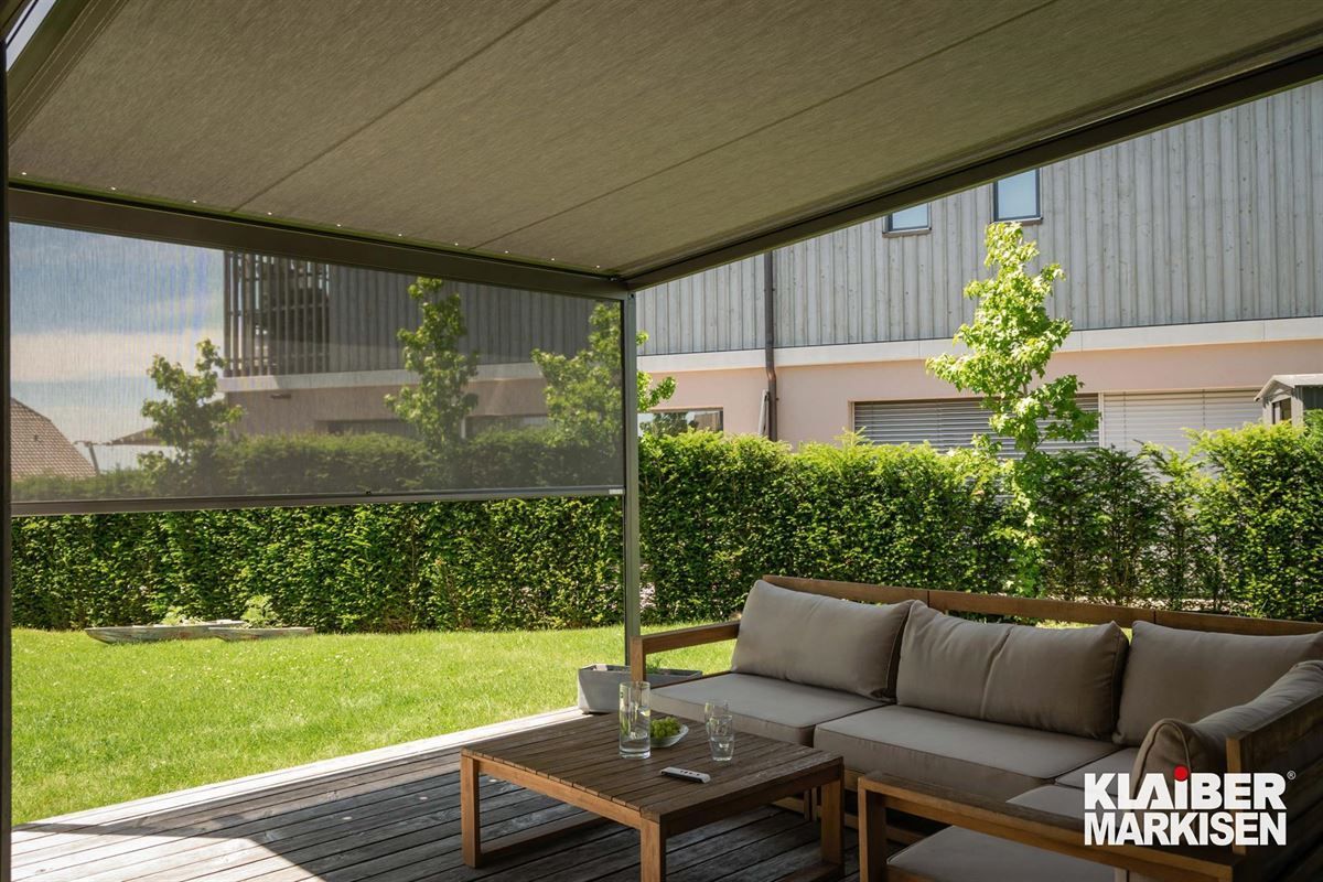 Eine Terrasse mit einer Couch und einem Tisch unter einem Baldachin.