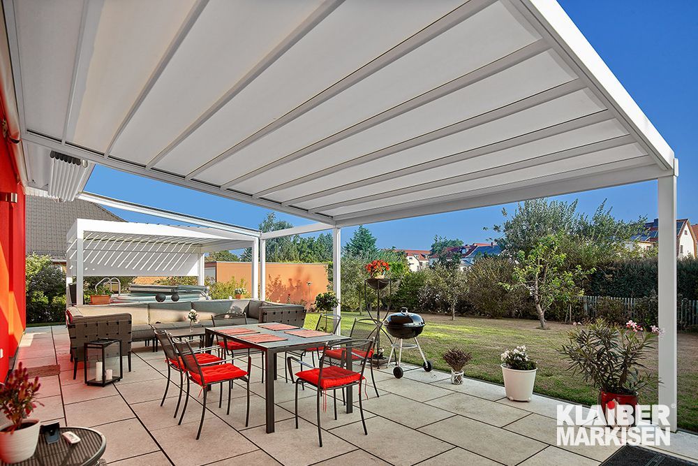 Eine Terrasse mit Tisch und Stühlen unter einem Baldachin.