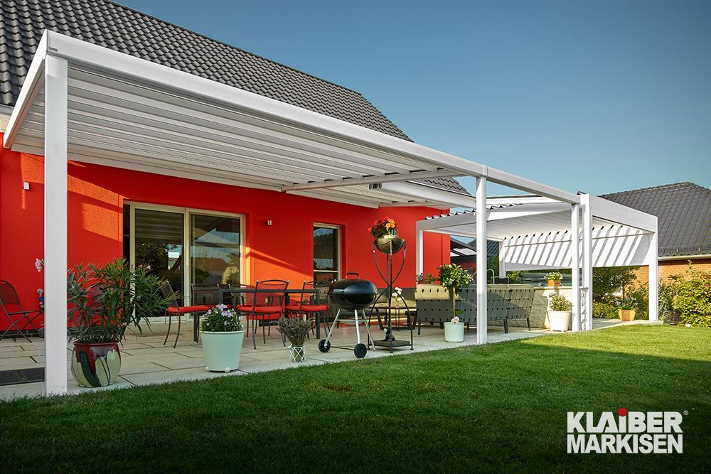 Ein rotes Haus mit einer weißen Pergola davor