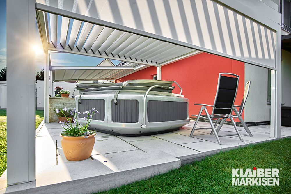Ein Whirlpool steht unter einer Pergola auf einer Terrasse.